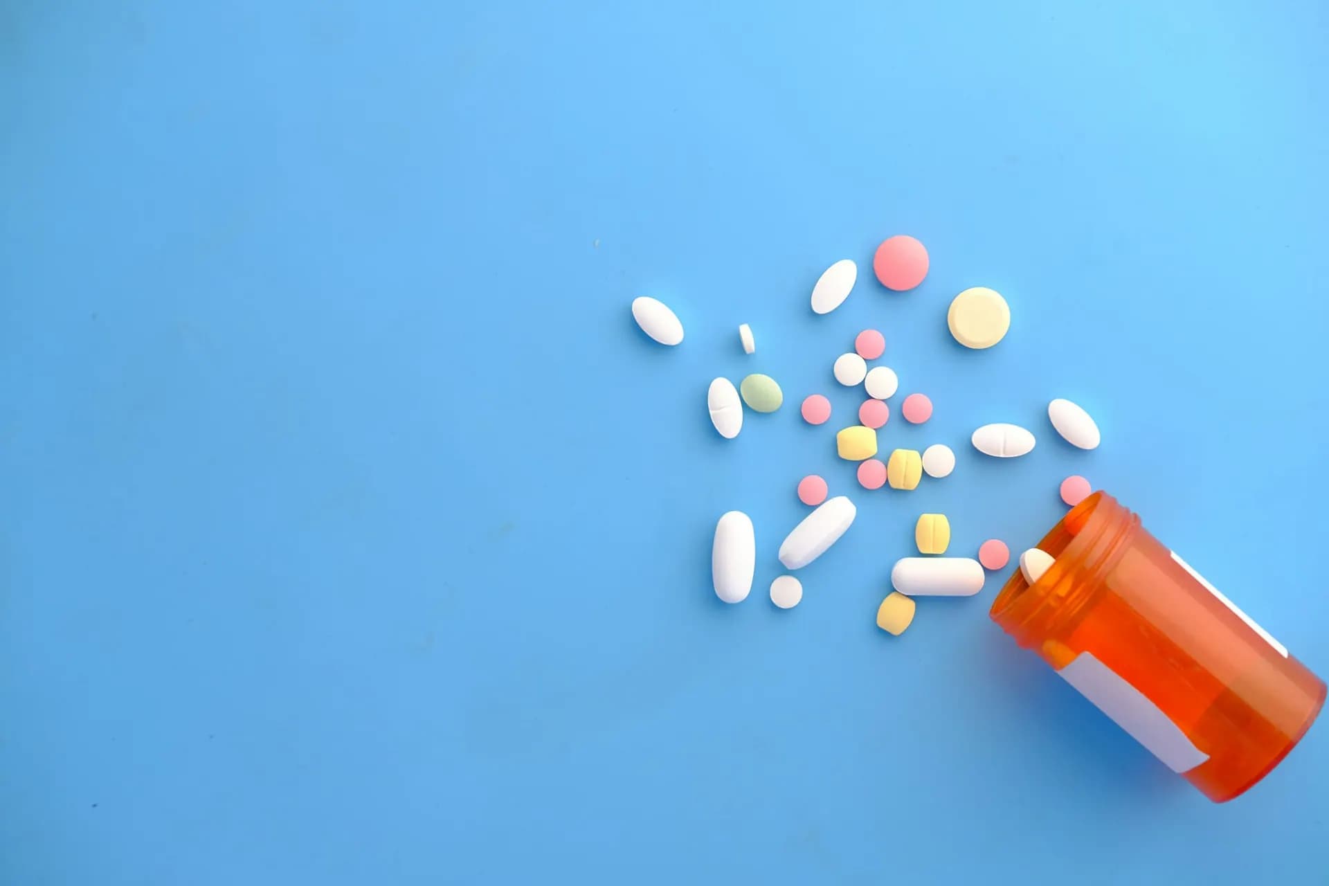 Tablets spilling from an orange bottle